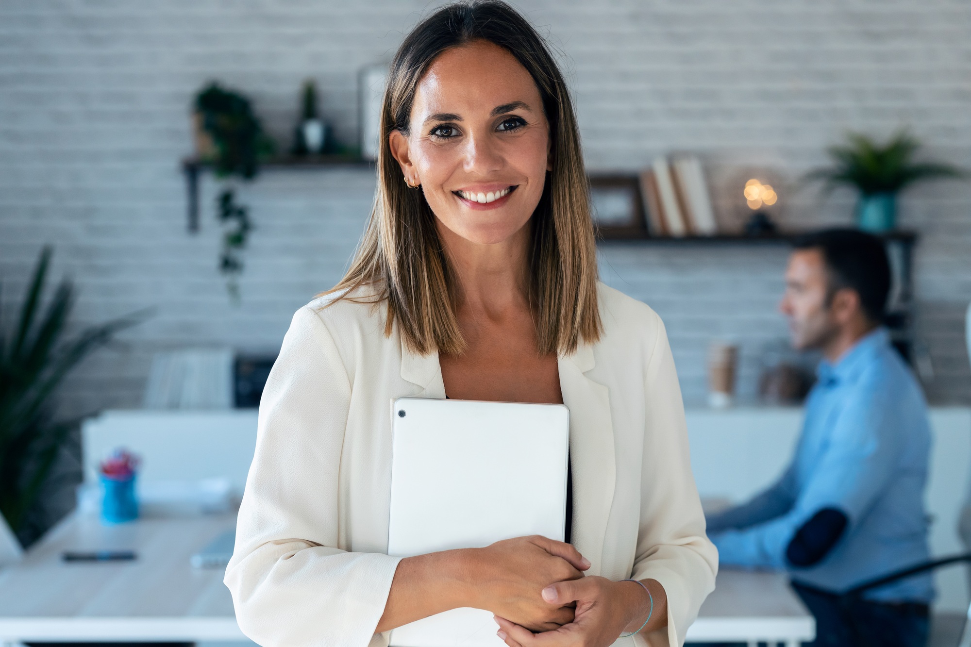 businesswoman looking at camera while holding digital tablet