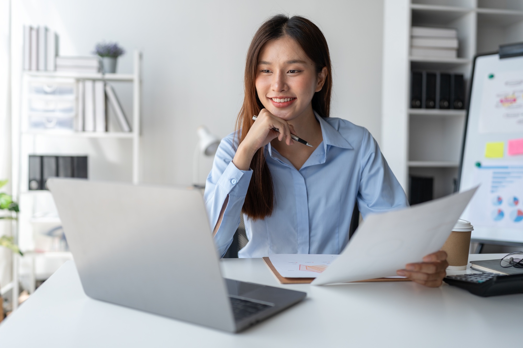 Asian businesswoman holding information sheet paper Business growth graphs, charts to analyze financ