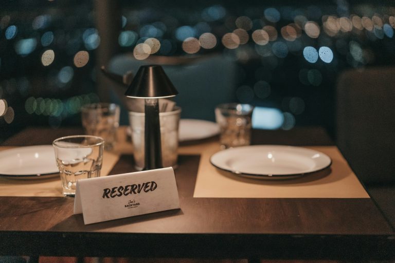A picture describing a fine dining restaurant table that is reserved for a special evening with your loved one with an elegant ambience, upscale table setting and a menu full of delicious dishes.